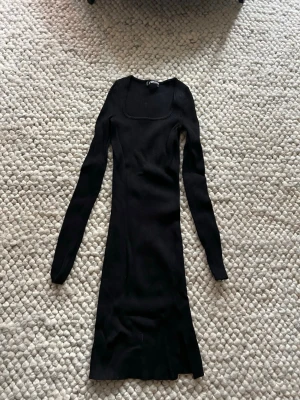 Svart ribbad långärmad klänning - En svart, ribbad långärmad klänning med fyrkantig halsringning och slits. Endast testad storlek xxs men passar nog någon i storlek xs/s väldigt stretchig