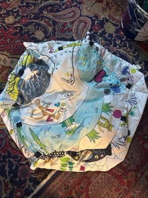 Lekmatta med djurmotiv från Kinderkraft - Rolig och färgglad lekmatta från Kinderkraft med djurmotiv och tecknade figurer. Mattan har en vit bas med inslag av blått, grönt, gult och rosa samt detaljer som blommor och vatten. Perfekt för att skapa en lekfull miljö.