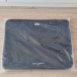 Datorväska från Dolce & Gabbana - Snygg och stilren datorväska från Dolce & Gabbana. Perfekt för att skydda din laptop med stil. Väskan är i nytt skick och har en praktisk dragkedja för säker förvaring. Passar perfekt för både vardag och arbete.