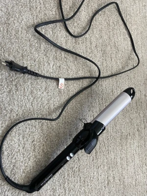 Babyliss locktång, 32mm - Elektrisk locktång från Babyliss med svart handtag och silverfärgad cylinder. Utrustad med lång sladd och kontrollknappar på handtaget. Perfekt för att skapa snygga lockar och vågor. 32mm. 