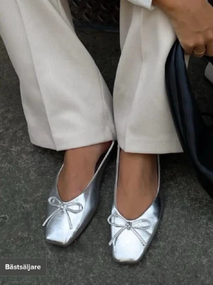 Silvriga ballerinaskor med rosett - Snygga ballerinaskor i metallic silver med. Endast använda till studenten! 