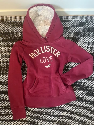 Vinröd hoodie från Hollister - Mysig vinröd hoodie från Hollister med vit text. Storlek S. Skicka gärna om du har frågor. Går att pruta🥰