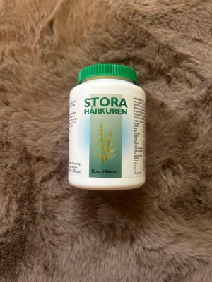 Stora Hårkuren kosttillskott - Burk med Stora Hårkuren kosttillskott, innehåller tabletter för hårvård. Vit plastburk med grön skruvkork och etikett med grön text och växtmotiv. Perfekt för dig som vill boosta håret med extra näring. Utgångsdatum november 2027. Mer än hälften kvar