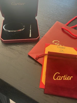  Love armband - Säljer ett ikoniskt  Love armband.  Armbandet har den klassiska skruvdesignen och kommer med originalförpackning, röd sammetspåse och skruvmejsel. Perfekt för dig som gillar exklusiva och tidlösa smycken.