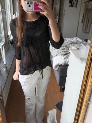 Svart transparent blus med spetsdetaljer!! - Säljer en svart transparent blus med fina spetsdetaljer. tillverkad i ett lätt, luftig material som ger en trendig look. Passar till en enkel vardags look och är perfekt till sommaren om man vill ha något som inte är för varmt men inte är kortärmad 💓