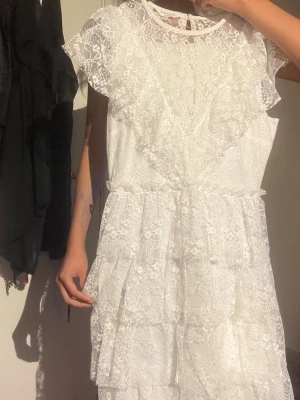 Vit spetsklänning med volanger - Supersöt vit klänning i spets med volang. Ordinarie pris 799kr