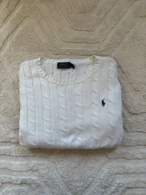 Polo Ralph Lauren Kabelstickad Tröja - Säljer en kabelstickad tröja från Polo Ralph Lauren i storlek S. Tröjan är i gott skick och har den klassiska loggan på bröstet. Perfekt för kyliga dagar! Kontakta mig för mer information eller bilder. 
