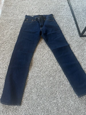 Mörkblå raka jeans från Levi's - Snygga mörkblå jeans från Levi's med klassisk rak passform och femficksmodell. Jeansen har kontrastsömmar och är tillverkade i slitstark denim. Perfekta för dig som gillar en tidlös och clean look.