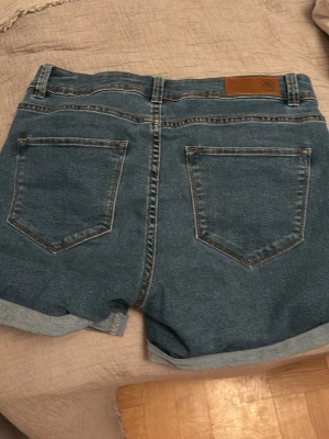 Blå denimshorts från Vero Moda - Jeans skotta i mörkare blå med stretch. 