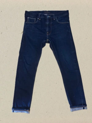 Nudie Jeans - Lean Dean Dry True Selvage (W31/L30) - Säljer ett par riktigt schyssta Nudie Jeans i den eftertraktade modellen Lean Dean Dry True Selvage. De är använda i några månader bara men redan har en slitning av mobil telefon och snusdosa i bakfickan.