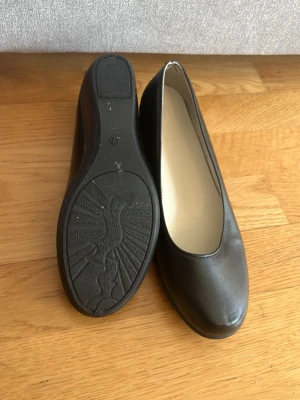 Svarta ballerinaskor med klack - Säljer oanvända svarta ballerinaskor med hög sula, aldrig använda då de var små i storlek. Är storlek 37 men passar nog dig som har storlek 36.