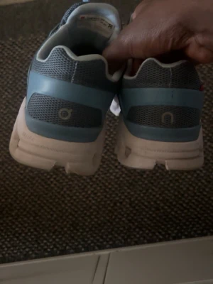 Blå On clout sneakers - Snygga sneakers från On clout i blått och grått med vit sula. Skorna har en sportig design med meshpaneler för bra ventilation och On-logga på sidan. Sulan är unik med sina dämpande segment och ovandelen är i textil och syntet.