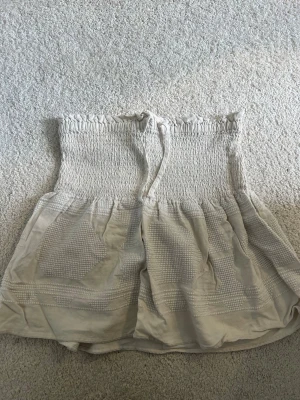 Beige kjol - En söt beige kjol med smockat material upptill och knytning vid midjan. Dessvärre finns lappen inte kvar, men den uppskattade storleken är S🩷