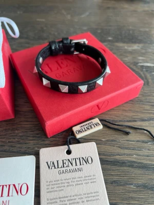 Valentino Garavani svart läderarmband - Helt oanvänt svart läderarmband från Valentino Garavani med silverfärgade nitar runt om. Justerbart spänne för perfekt passform. Snygg accessoar. 