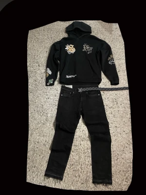 Svarta jeans  - Svarta skinny jeans med fem fickor och råa, fransiga benslut. Jeansen har en klassisk design med smal passform och är tillverkade i denim. Perfekta för en streetwear-look.