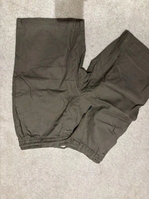 Mörkgröna/bruna  linneshorts från Dressmann | strl S - Säljer ett par bruna shorts från Dressmann i skön linnemix. De har elastisk midja och enkel design utan synliga detaljer. Perfekta för varma dagar och riktigt bekväma att bära.