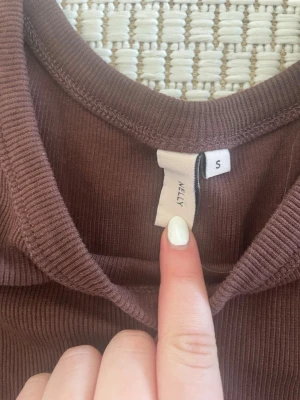 Brun ribbad linnetopp från Nelly - Snygg brun ribbad linnetopp från Nelly med breda axelband och rund halsringning. Perfekt att styla med jeans eller kjol för en chill look. Materialet är mjukt och stretchigt för extra komfort.