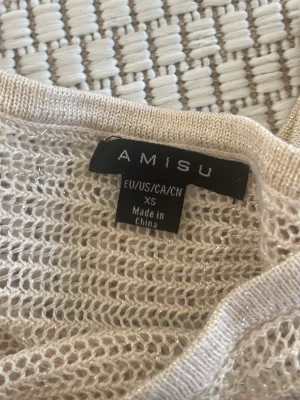 Beige stickad tröja från Amisu - Snygg beige stickad tröja från Amisu i storlek XS. Tröjan har ett genombrutet, luftigt mönster och ribbade muddar vid ärmslut och nederkant. Perfekt för lager-på-lager och en chill stil.