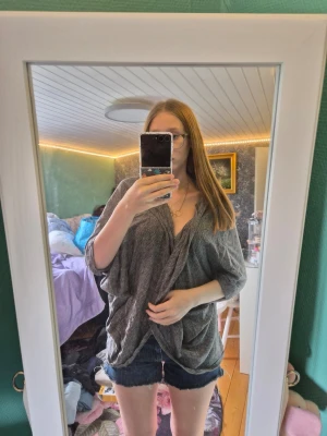 Grå kofta  - Säljer en kofta med trekvartsärm. Toppen har en loose passform och är tillverkad i ett mjukt, lätt material som känns skönt mot huden. Perfekt att styla med jeansshorts eller kjol för en chill look.