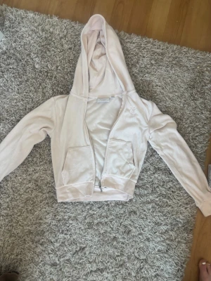 Ljusrosa velour hoodie Juicy Couture - Säljer en ljusrosa hoodie från Juicy Couture i mjuk velour. Hoodien har dragkedja, två fickor fram och en broderad logga på bröstet. Perfekt för en chill och trendig look. Klassisk passform och stor huva.