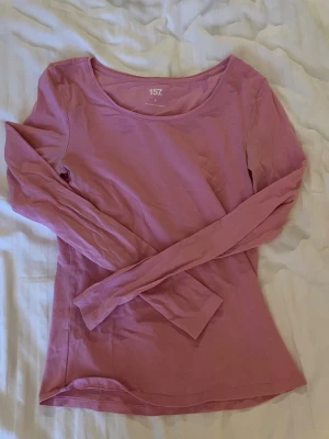 Rosa långärmad topp från 157 - En basic rosa långärmad topp från 157 i mjuk bomullsblandning med lite stretch. Enkel och stilren design med rund halsringning, perfekt att matcha med jeans eller kjol.