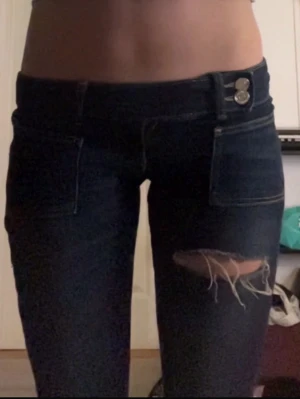 Lågmidjade jeans  - Supersnygga lågmidjade jeans med två hål på knäna och ett på låret 💕 Slutsålda i denna storleken på hemsidan! Superskönt och strechigt material! Lite sönder längst ner (bild 3) men inget man märker 🥰