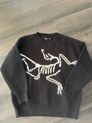 Arc’teryx - Säljer en stickad tröja från Arc’teryx. Storlek M, men har en oversized/baggy passform.  Tröjan är svart med ett tydligt motiv på framsidan. Den är helt oanvänd och i nyskick utan några defekter.  Passar bra till en avslappnad stil och funkar året runt