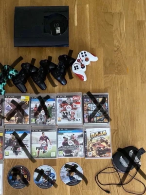 PlayStation 3 med handkontroller - PlayStation 3 spelkonsol i svart med fyra handkontroller, varav en är vit och röd. Konsolen har en klassisk, rektangulär form och är tillverkad i plast. Perfekt för dig som gillar gaming och vill spela både solo och med vänner.