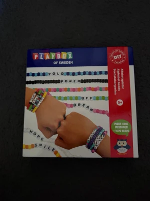 Playbox pärlarmbandskit med bokstäver - Gör egna armband med detta DIY-kit från Playbox! Innehåller över 1000 färgglada plastpärlor och bokstavspärlor så du kan skapa personliga budskap som 'YOLO', 'BFF' och 'SMILE'. Perfekt för dig som gillar att pyssla och vill ha unika accessoarer.