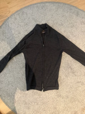 Oscar Jacobson zip - Utrensning av garderoben! Säljer den här super fräscha Oscar Jacobson zip tröjan. Fortfarande super fint skick. Lite mer av de mörkgråa hållet. 100% merino ull. Tveka inte på höra av dig!!