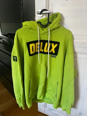 ODZ x delux hoodie - ODZ x Delux hoodie i neon/grön färg med gul fuzzy/lurvig logga.   Hoodien är i väldigt fint skick då den bara använts några få gånger. Färgen och detaljerna sticker ut riktigt mycket i verkligheten och kvaliteten känns tung och premium.  Passar perfekt för dig som gillar äldre svensk streetwear/merch eller bara vill ha något unikt som inte alla andra har.  Storlek: XL, använt den som oversized hoodie då jag har S Skick: Väldigt fint skick  Pris: 799