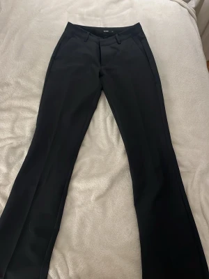Svarta kostymbyxor med bootcut - Snygga svarta low waist kostymbyxor som är lite bootcut. Uppsprettade längst ned, men är nog inte så svår att sy ihop om dem skulle vara för långa. Dem är från bikbok och är i storlek 34