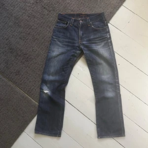 Mörkblåa Nudie Dry Slim Jim Jeans - Nudie Jeans med bra fades. | W29 L32. | Fint skick lagade i skrevet samt liten slitning på låret/knäet. | Längd: 93cm Midja: 37cm. | Skriv vid minsta fundering, pris ej hugget i sten.