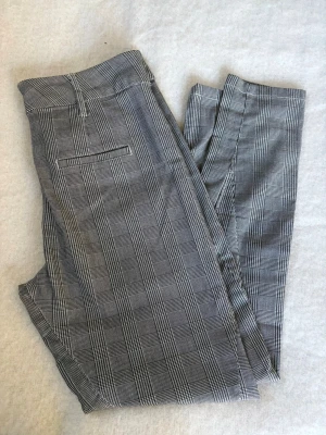 Boyfriend byxor slim fit strl 34 - Snygga grå kostymbyxor i boyfriend modell med klassiskt rutigt mönster och raka ben. Byxorna har hällor för skärp, snedställda fickor fram och en passpoalficka bak.