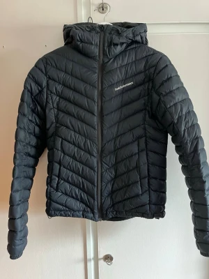 Svart pufferjacka från Peak Performance - Snygg svart pufferjacka från Peak Performance med huva och dragkedja framtill. Jackan har ett quiltat mönster i chevron-stil, två sidofickor och diskret logga på bröstet. Perfekt för kalla vinterdagar och riktigt skön att bära. En peak jacka som är för liten för mig. Men den är i väldigt fint skick. Dock lite liten i storleken det är en M men skulle säga att den mer än som en S. Skriv för fler bilder! Har en liten skada se bild 3
