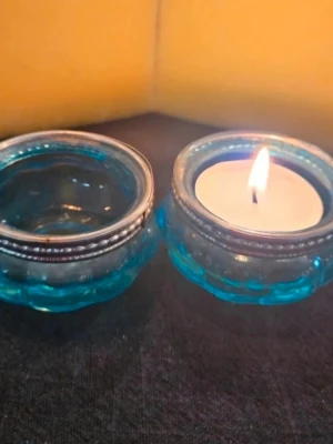 Blåa ljuslyktor i glas - Två runda ljuslyktor i blått glas med dekorativ silverkant. Perfekta för värmeljus och ger ett mysigt sken. Säljs tillsammans och passar snyggt som dekoration i hemmet.