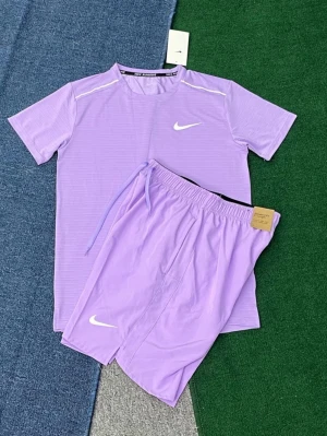 Lila Nike träningsset t-shirt & shorts - Snyggt lila träningsset från Nike med matchande t-shirt och shorts. T-shirten har korta ärmar och vita detaljer vid axlarna samt Nike-logga på bröstet. Shortsen har resår i midjan, dragsko och vit Nike-logga på benet. Perfekt för gym eller löpning.