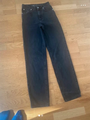 Svarta straight jeans waist 24 längd 32 - Säljer ett par svarta straight fit jeans med hög midja och klassisk femficksdesign. Jeansen har storlek waist 24 och längd 32. Perfekta för dig som gillar en tidlös och enkel stil.