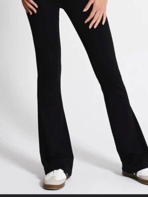 Svarta utsvängda leggings - Säljer ett par svarta yoga pants med utsvängda ben. De har en hög midja och är tillverkade i ett stretchigt material som sitter skönt på kroppen. Perfekta för dig som gillar en trendig och bekväm stil.