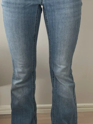 Ljusblå bootcut jeans - Snygga ljusblå bootcut-jeans med låg midja från Vero Moda. Jag är ca 162 cm lång och på bilden ser du hur byxorna sitter på mig.  Jeansen är i bra skick. Det finns några små hål vid kanten, men det är knappt synligt när byxorna är på (se bild 4). Byxorna är uppsydda cirka 1,5 cm. Ordnarie pris: 599 kr   Jag säljer även flera andra jeans – kolla gärna min profil! Hör av dig om du har frågor 😊