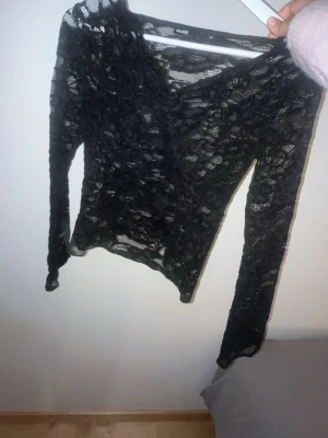 Svart spets tröja  Bik Bok - Snygg svart långärmad spetsblus från Bik Bok i storlek M. Blusen har v-ringning och är helt i genomskinlig spets med blommigt mönster. Perfekt att styla lager på lager för en trendig look. Helt ny och oanvänd lappen är inte kvar