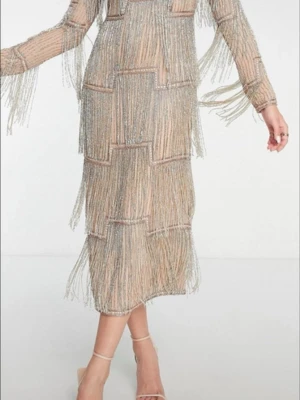 Glittrig fransklänning i silver - Supercool glittrig klänning med långa fransar i silver och beige. Klänningen har lång ärm och är täckt av skimrande detaljer som ger en riktigt festlig look. Perfekt för dig som vill sticka ut och glänsa på nästa event!