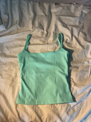 Teal  linnetopp med smala band - Köpt i Italien 🇮🇹 Säljer en fräsch teal linnetopp med smala axelband. Toppen har en enkel och stilren design som passar perfekt till sommaren. Materialet känns mjukt och stretchigt, vilket gör den bekväm att bära hela dagen. Aldrig använt då den tyvärr var för liten ❤️