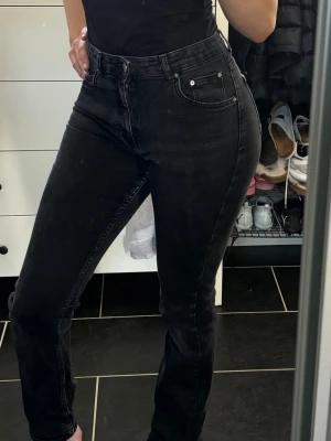 Svarta bootcut jeans - Säljer ett par svart/gråa hög/medelmidjade jeans (går precis under naveln). Köptes för 2 år sedan på gina och är använda fåtal gånger. (Jag är 170). Skriv för fler bilder.