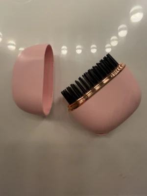 Rosa mini värmeborste - En mini värmeborste i färgen ljusrosa. Aldrig använt. Den är trådlös och är bärbar. Man laddar den med en laddare som kommer med i paketet. Den har tre lägen: 160,180,200 grader. Mycket bra och får plats i väskan om man vill ta me den någonstans. PostNord prioriteras.