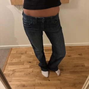 Mörkblå raka jeans vintage  - Säljer ett par mörkblå jeans med rak passform och klassisk femficksdesign. Jeansen har låg midja och stängs med knapp och dragkedja. Perfekta för en avslappnad och trendig look. Midjemått: 27 rakt över, motsvarar en 36/S. Innerbenslängd: 83 och passar någon som är 170+ 