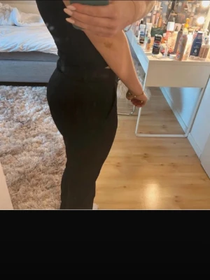 Svarta kostymbyxor med rak passform - Snygga svarta kostymbyxor med rak passform och hög midja. Byxorna har klassisk design med knapp och dragkedja framtill. Perfekta för en stilren look och lätta att matcha med olika toppar. Ifrån bikbok