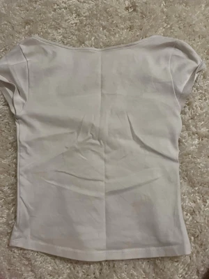 Vit croppad topp med rund hals - Säljer en enkel och stilren vit croppad topp med rundad halsringning och korta ärmar. Toppen är tillverkad i mjuk bomull och har en clean look som passar till det mesta. Perfekt till jeans eller kjol för en avslappnad vibe.