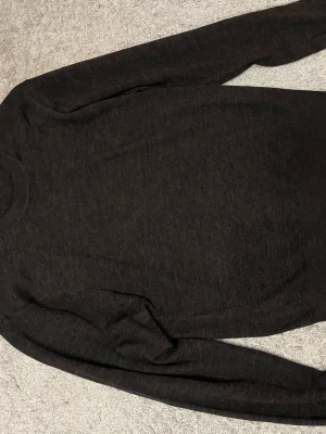 Mörkbrun stickad tröja från Norvie - Snygg mörkgbrun stickad tröja från Norvie med rund halsringning och långa ärmar. Tröjan har en enkel och stilren design som passar perfekt till lager på lager och är gjord i mjukt material för extra komfort.