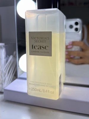 Victoria's Secret Tease Crème Cloud mist - Fräsch och lyxig body mist från Victoria's Secret i doften Tease Crème Cloud. Flaskan är genomskinlig med svart lock och har en stilren beige etikett. Innehåller 250 ml och ger en mjuk, söt och krämig doft som känns modern och feminin.